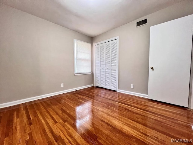 unfurnished bedroom with hardwood / wood-style floors and a closet