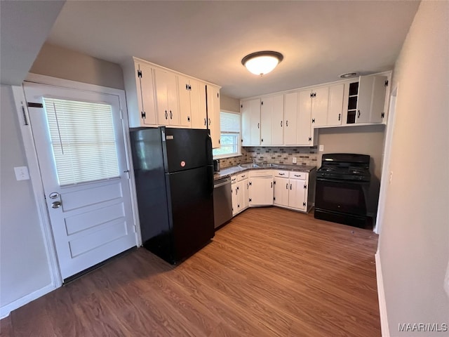 kitchen featuring hardwood / wood-style floors, backsplash, black appliances, and white cabinets