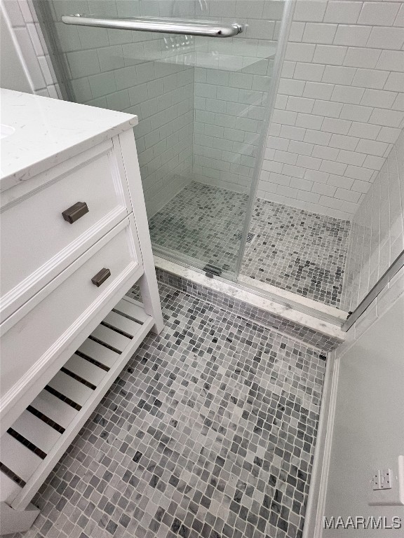 bathroom with tile patterned flooring, vanity, and walk in shower