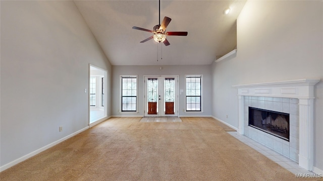 unfurnished living room with ceiling fan, light colored carpet, high vaulted ceiling, and a tile fireplace