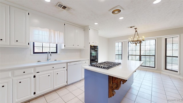 kitchen with sink, light tile patterned floors, dishwasher, a kitchen island, and white cabinets