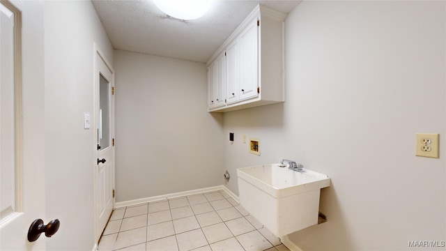 clothes washing area featuring cabinets, washer hookup, a textured ceiling, and light tile patterned floors