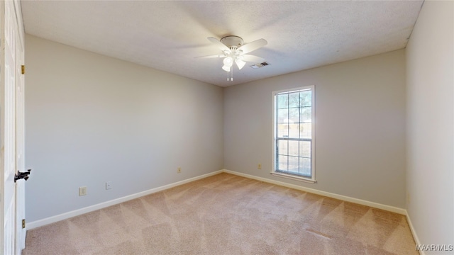 empty room with light colored carpet, a textured ceiling, and ceiling fan