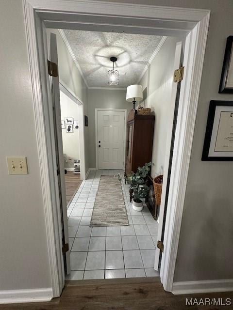 doorway with crown molding, light tile patterned floors, and a textured ceiling