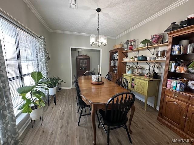 dining room featuring hardwood / wood-style flooring, ornamental molding, a textured ceiling, and a notable chandelier