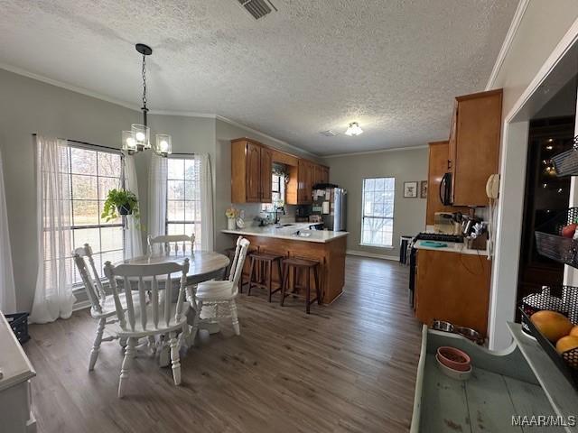 dining space with hardwood / wood-style flooring, ornamental molding, an inviting chandelier, and a textured ceiling