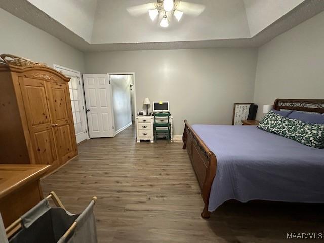 bedroom with a raised ceiling, dark hardwood / wood-style floors, ceiling fan, and a high ceiling