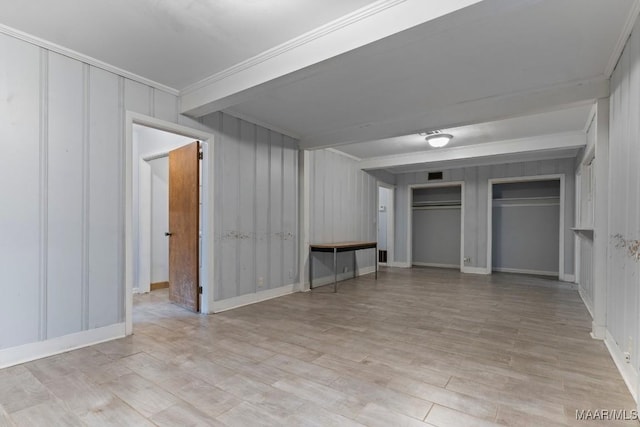 unfurnished bedroom with ornamental molding, beam ceiling, a closet, and light hardwood / wood-style flooring