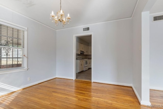 spare room with ornamental molding, a chandelier, and light wood-type flooring