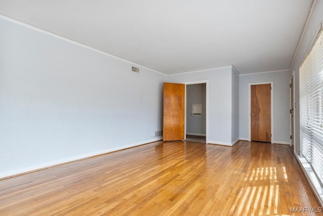 empty room featuring crown molding and light wood-type flooring