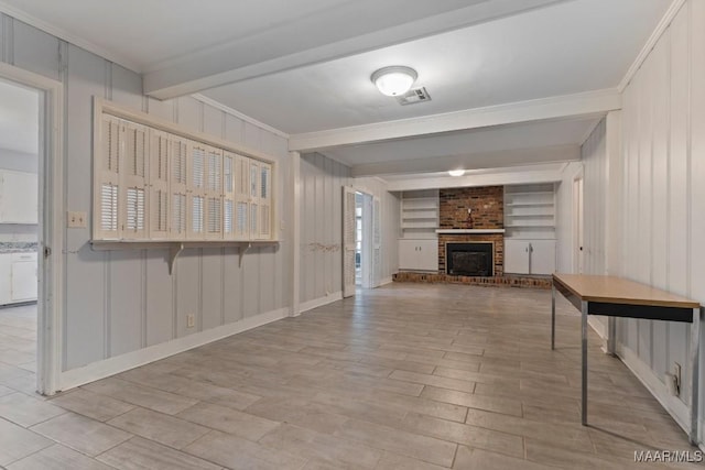 unfurnished living room with built in shelves, crown molding, beam ceiling, and a brick fireplace