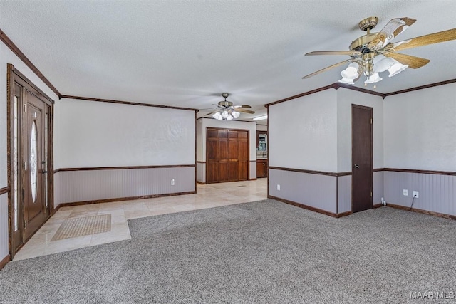 carpeted spare room with ceiling fan, crown molding, and a textured ceiling