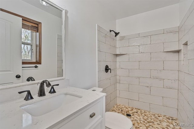 bathroom with vanity, toilet, and a tile shower