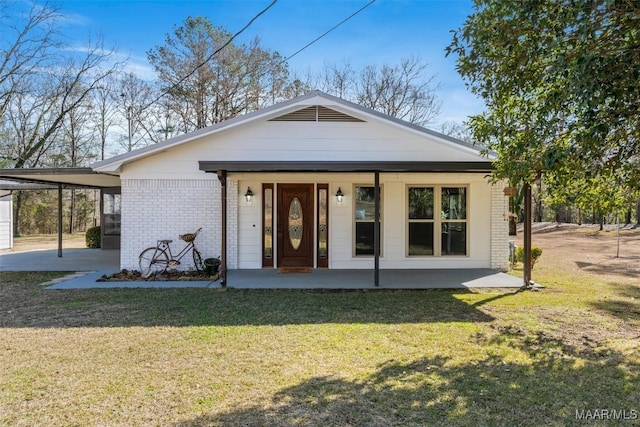 back of house featuring a porch, a carport, and a lawn