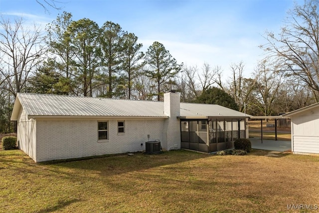 rear view of property with central AC unit, a yard, and a sunroom