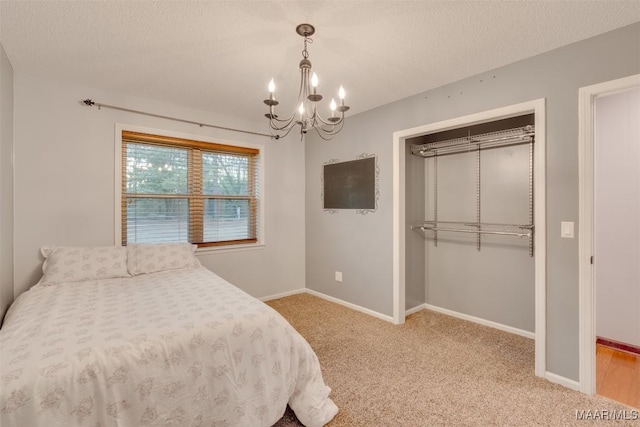 carpeted bedroom featuring a chandelier, a textured ceiling, and a closet