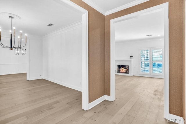 hall with a notable chandelier, crown molding, and light hardwood / wood-style floors