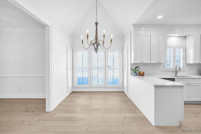 kitchen featuring decorative light fixtures, tasteful backsplash, sink, white cabinets, and light hardwood / wood-style floors