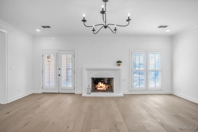 unfurnished living room with ornamental molding, an inviting chandelier, light hardwood / wood-style floors, and french doors