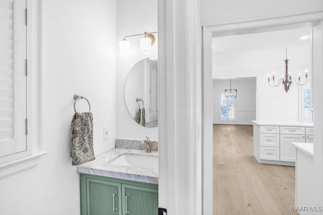 bathroom with an inviting chandelier, vanity, and hardwood / wood-style flooring