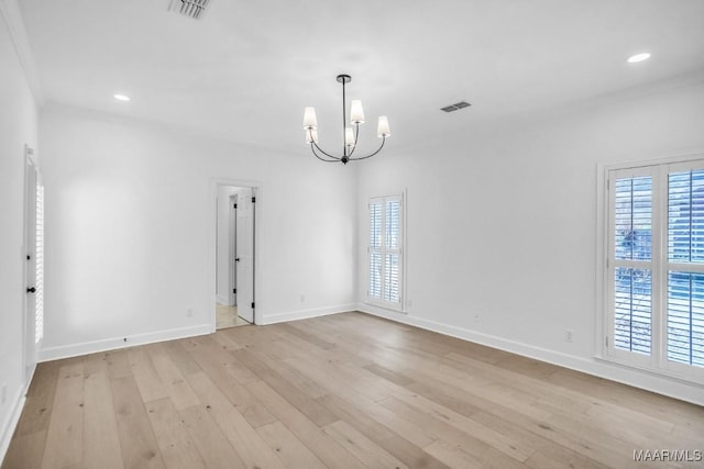 unfurnished room featuring an inviting chandelier, crown molding, and light hardwood / wood-style floors