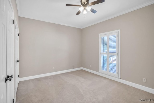 empty room featuring ceiling fan, light colored carpet, and crown molding