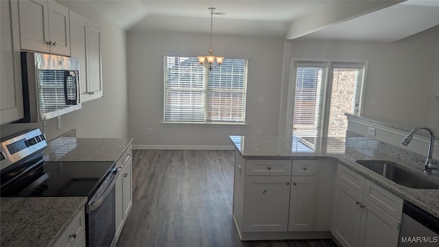 kitchen with appliances with stainless steel finishes, a wealth of natural light, sink, white cabinets, and hanging light fixtures