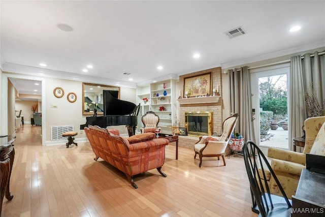 living room featuring crown molding, a fireplace, and light wood-type flooring