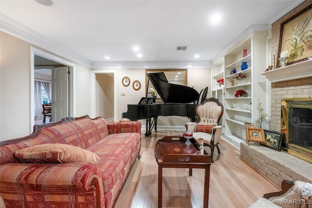 living room with built in shelves, a fireplace, ornamental molding, and light wood-type flooring