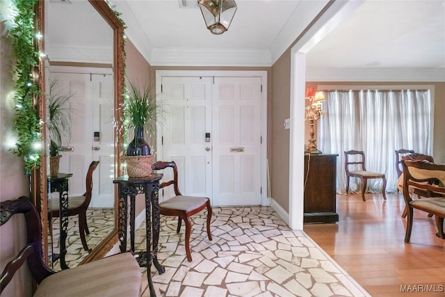 foyer with ornamental molding and light hardwood / wood-style floors