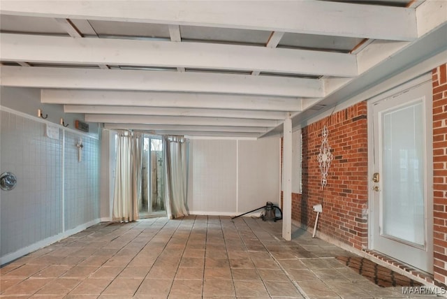 basement featuring tile patterned floors and brick wall