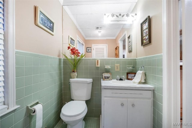 bathroom featuring ornamental molding, vanity, toilet, and tile walls