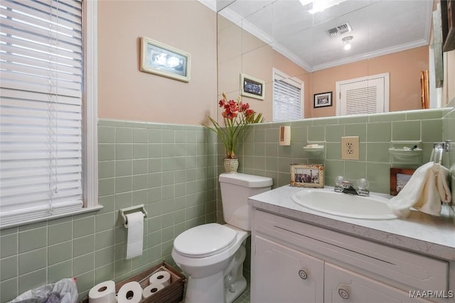 bathroom with crown molding, vanity, toilet, and tile walls