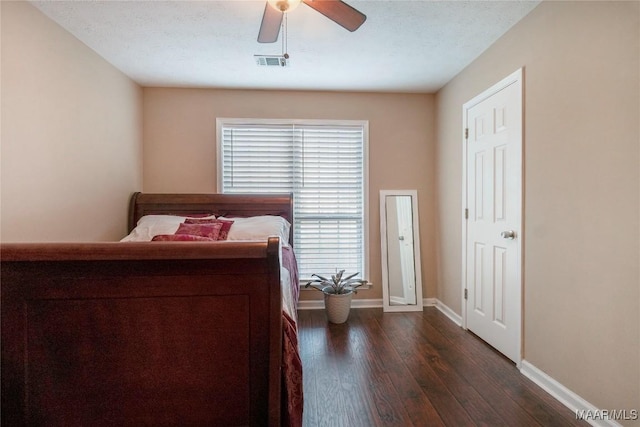 bedroom with ceiling fan, dark hardwood / wood-style flooring, and a textured ceiling