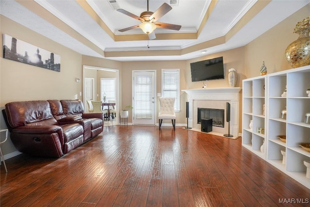 living room with crown molding, hardwood / wood-style flooring, a raised ceiling, and ceiling fan