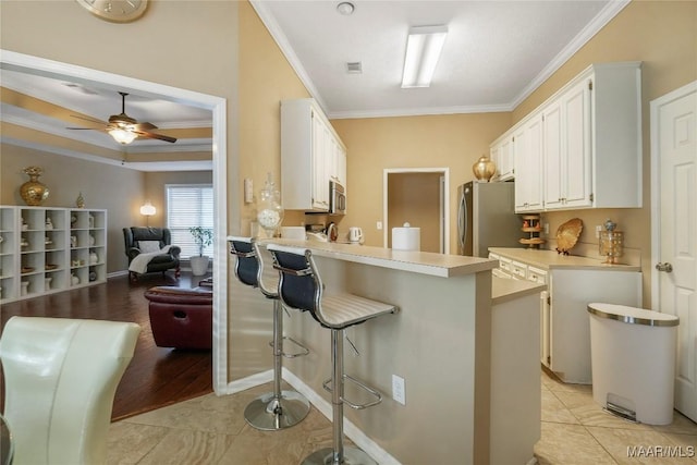 kitchen featuring stainless steel appliances, white cabinetry, a breakfast bar, and kitchen peninsula