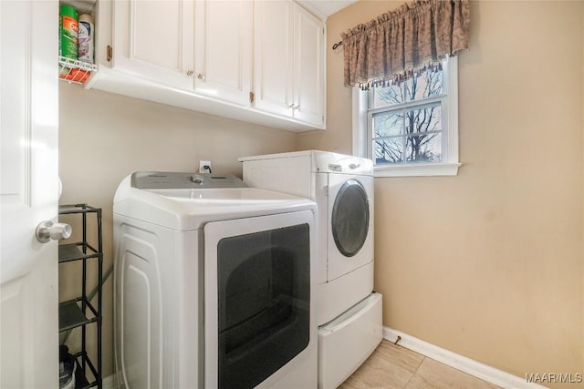 clothes washing area featuring washing machine and dryer, cabinets, and light tile patterned flooring