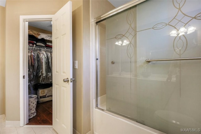 bathroom featuring tile patterned flooring and bath / shower combo with glass door