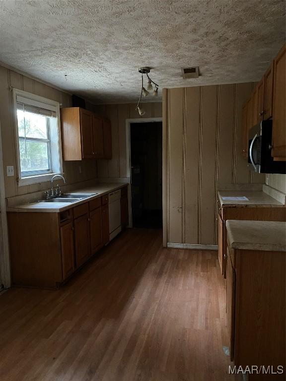 kitchen with white dishwasher, light hardwood / wood-style floors, sink, and a textured ceiling