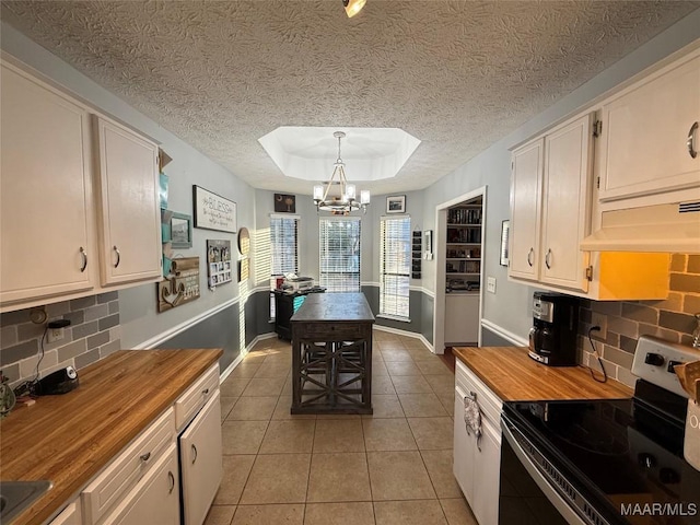 kitchen featuring electric stove, wooden counters, a raised ceiling, and pendant lighting