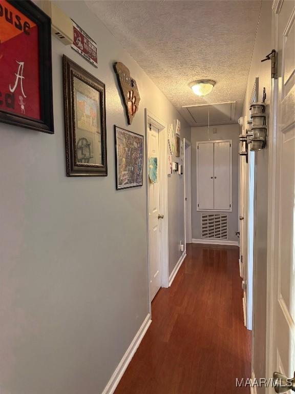 hallway featuring dark wood-type flooring and a textured ceiling