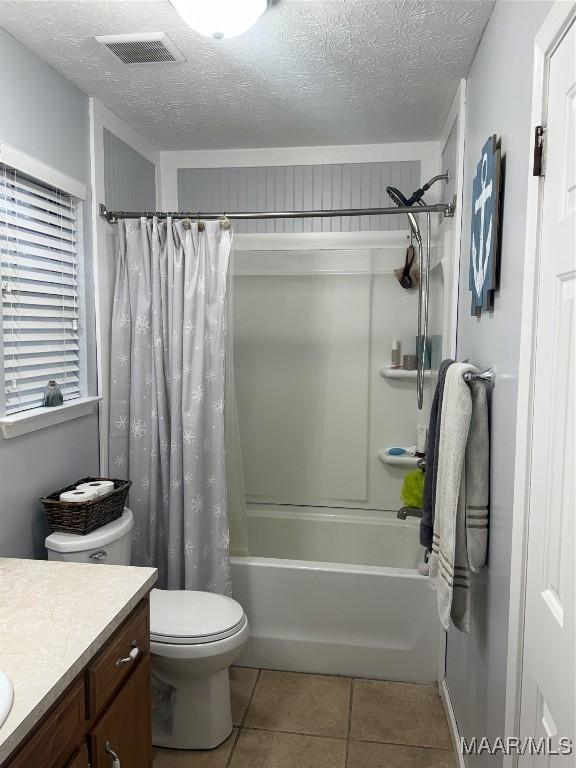 full bathroom with tile patterned floors, vanity, shower / bathtub combination with curtain, and a textured ceiling