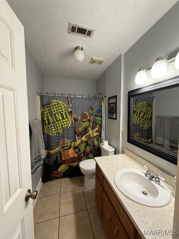 bathroom with walk in shower, toilet, a textured ceiling, vanity, and tile patterned flooring