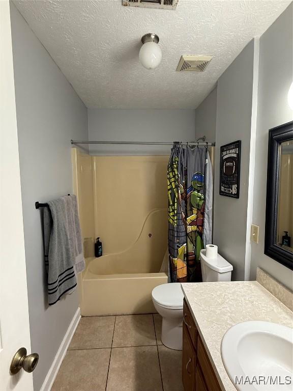 full bathroom featuring shower / tub combo with curtain, tile patterned flooring, vanity, toilet, and a textured ceiling