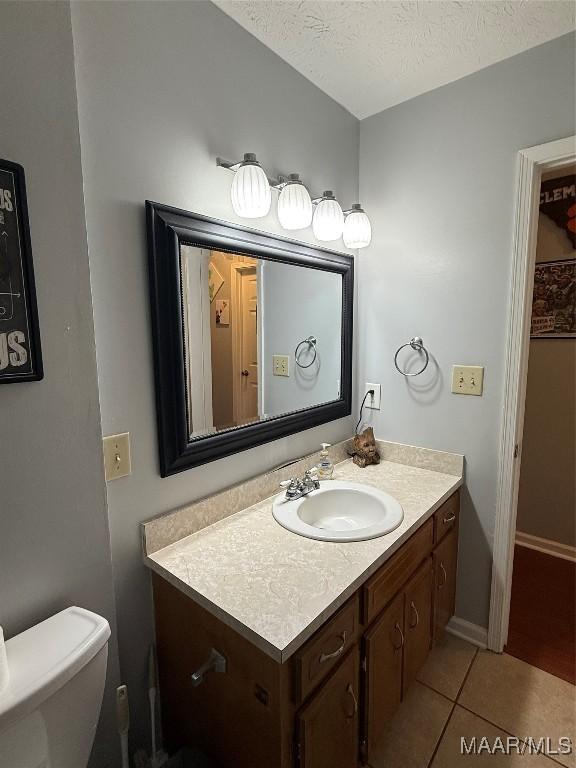 bathroom with vanity, tile patterned floors, toilet, and a textured ceiling