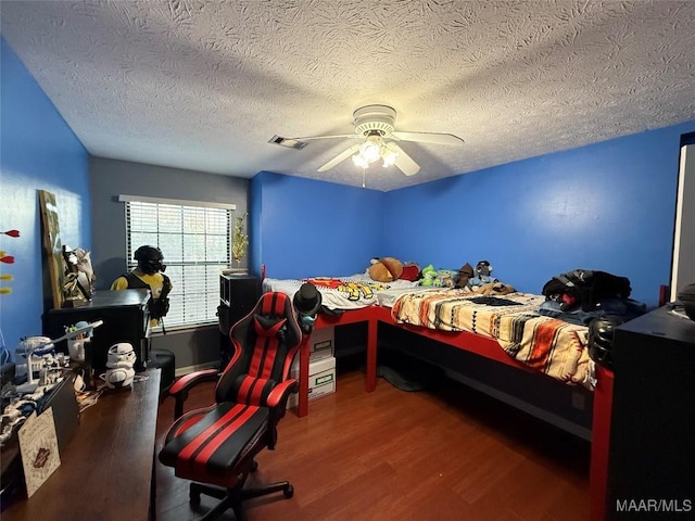 bedroom featuring ceiling fan, wood-type flooring, and a textured ceiling