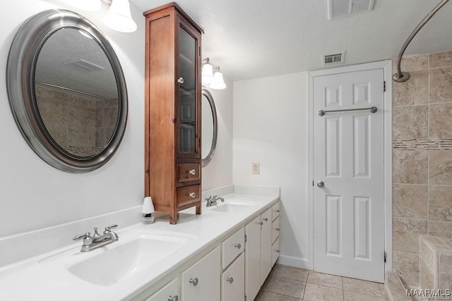 bathroom featuring tile patterned flooring, vanity, and a textured ceiling