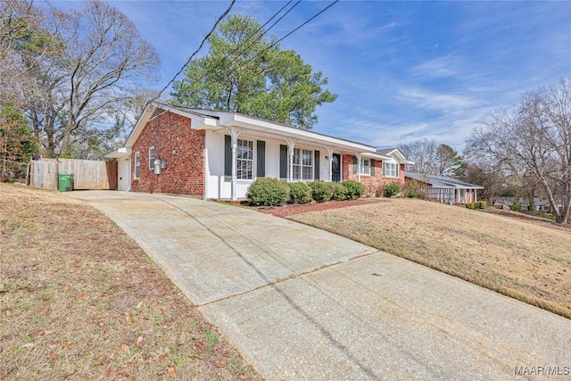 ranch-style home featuring covered porch and a front lawn