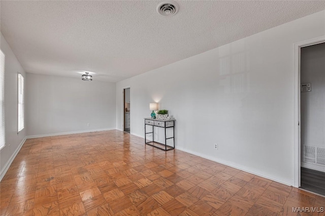 unfurnished room featuring parquet flooring and a textured ceiling