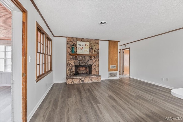 unfurnished living room with dark hardwood / wood-style floors, a stone fireplace, a textured ceiling, and crown molding